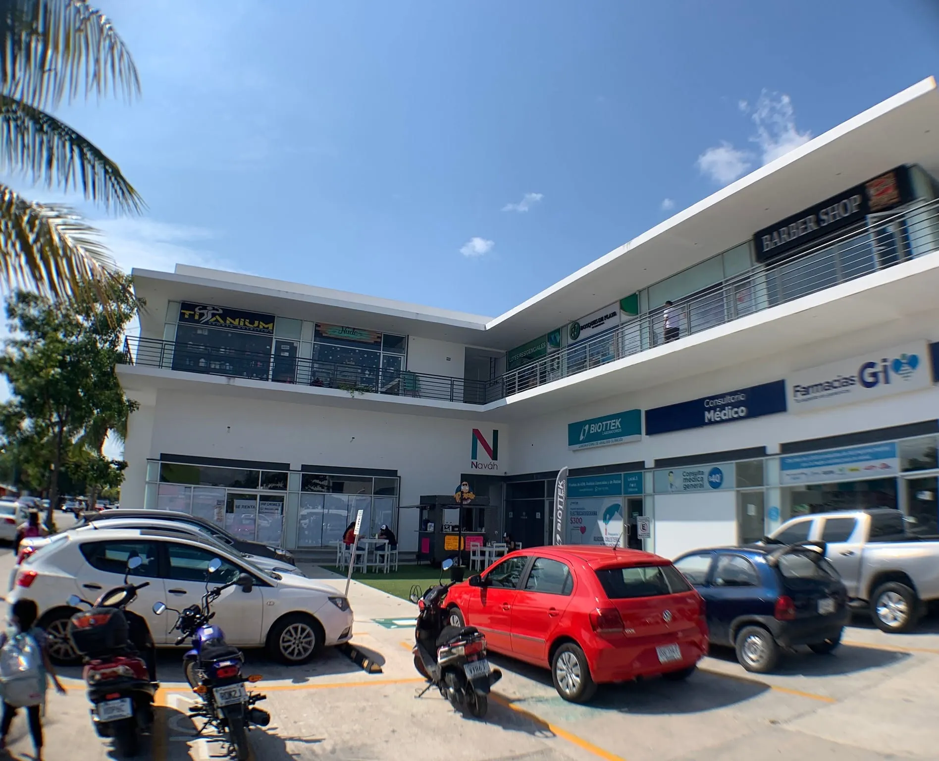 Fachada de Plaza Naváh: locales comerciales en dos niveles con pasillo corrido en la planta alta y estacionamiento al frente